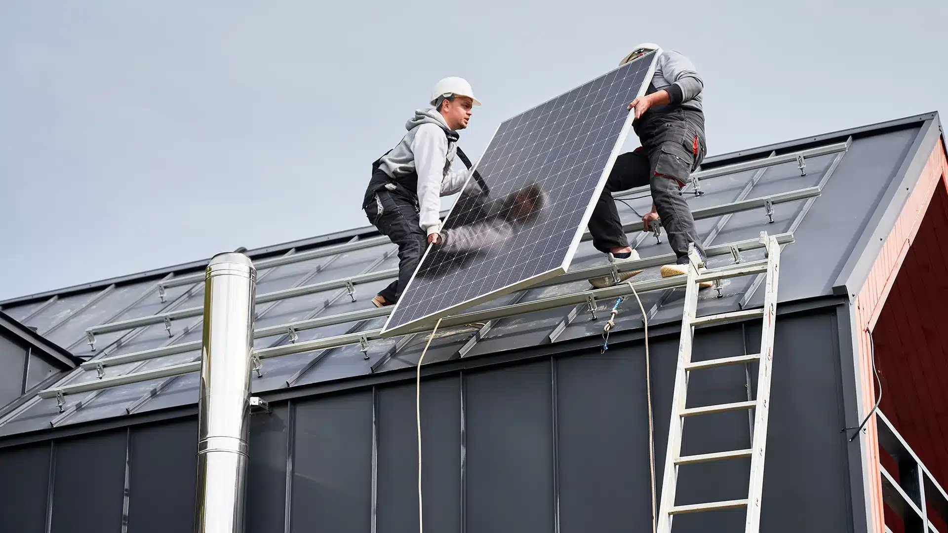 Équipe d'ouvriers qui équipe la toiture d'une maison de panneaux solaires photovoltaïques