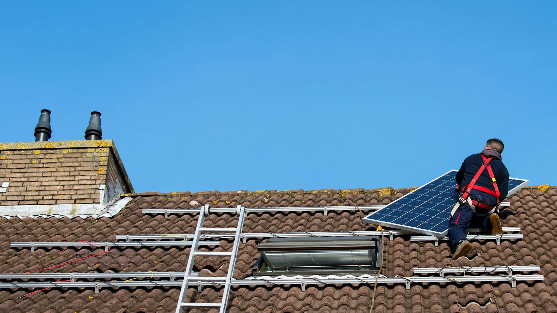 Ouvrier qui équipe la toiture d'une maison de panneaux solaires photovoltaïques