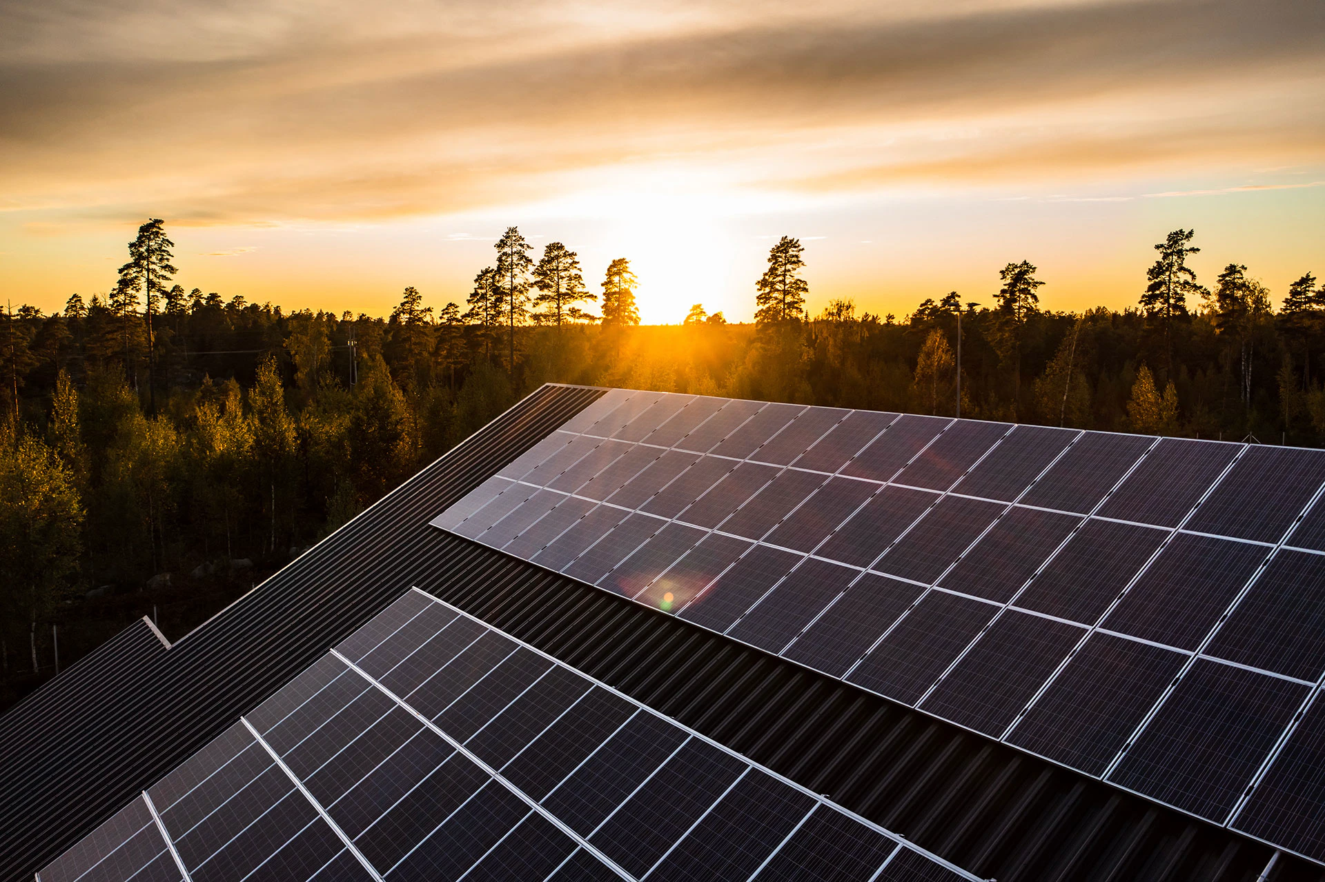 Maison équipée de panneaux solaires sur le toit avec un couché de soleil en arrière plan.